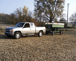 truck pulls combine hopper trailer through field
