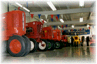long row of restore tractors in warehouse with highly polished floors